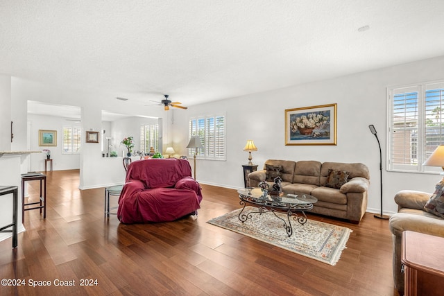 living area with ceiling fan, a textured ceiling, baseboards, and wood finished floors