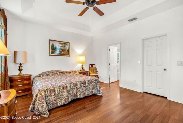 bedroom featuring a raised ceiling, visible vents, and wood finished floors