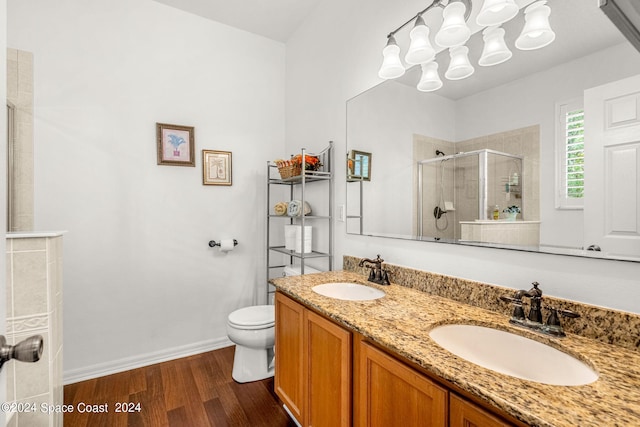 full bath with double vanity, wood finished floors, a stall shower, and a sink