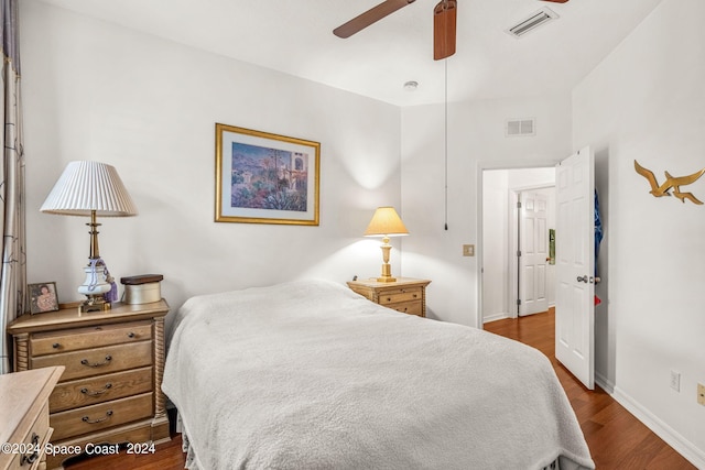 bedroom featuring dark wood-style floors, visible vents, baseboards, and a ceiling fan