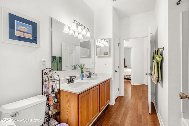 bathroom featuring double vanity, wood finished floors, a sink, and toilet