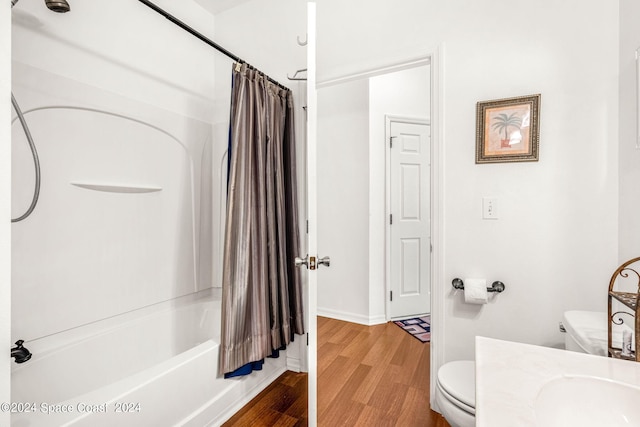 bathroom featuring toilet, shower / bath combo, vanity, wood finished floors, and baseboards