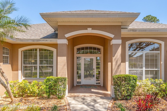 property entrance with stucco siding and roof with shingles