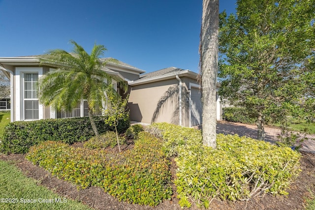 view of side of home featuring an attached garage and stucco siding