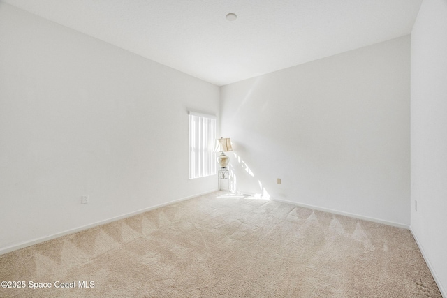 spare room featuring carpet flooring and baseboards