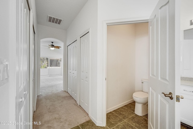 bathroom featuring baseboards, visible vents, a ceiling fan, toilet, and tile patterned flooring