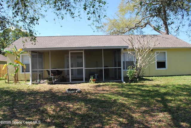 back of house with stucco siding, roof with shingles, a sunroom, and a yard