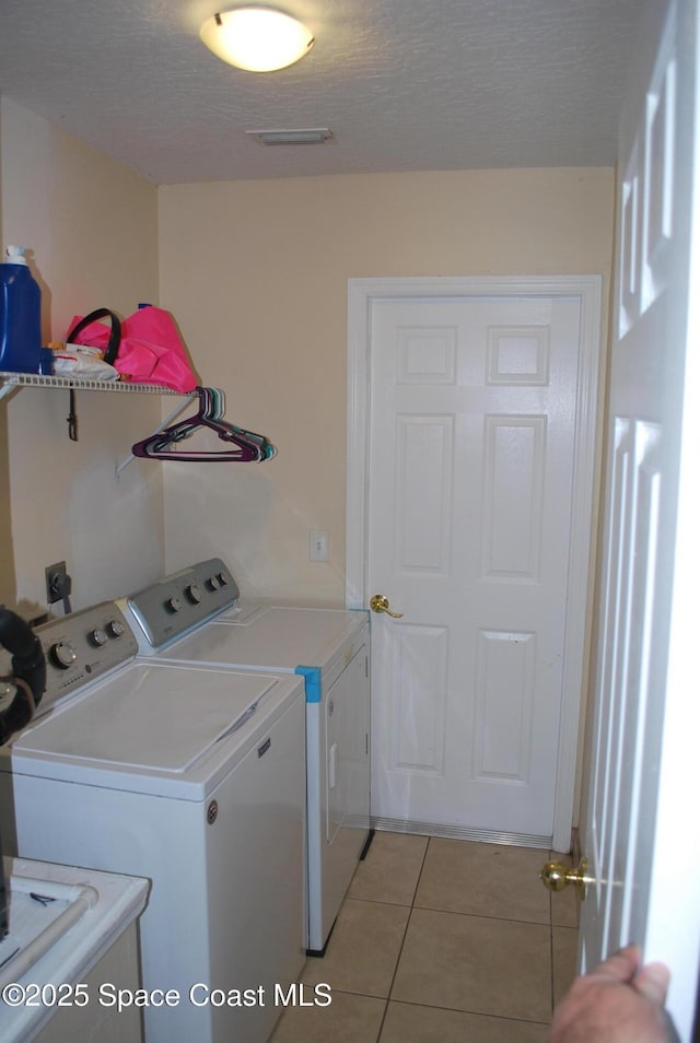 laundry room with light tile patterned floors, laundry area, a textured ceiling, and washing machine and dryer