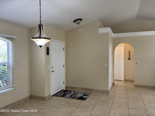 entrance foyer with arched walkways, baseboards, vaulted ceiling, and light tile patterned flooring