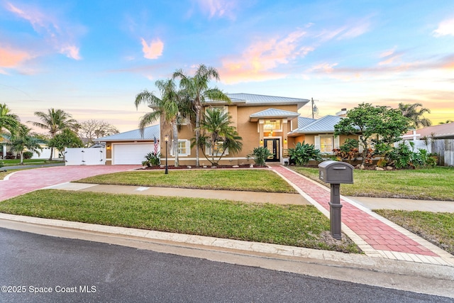 view of front of house with a garage, a front lawn, decorative driveway, and stucco siding