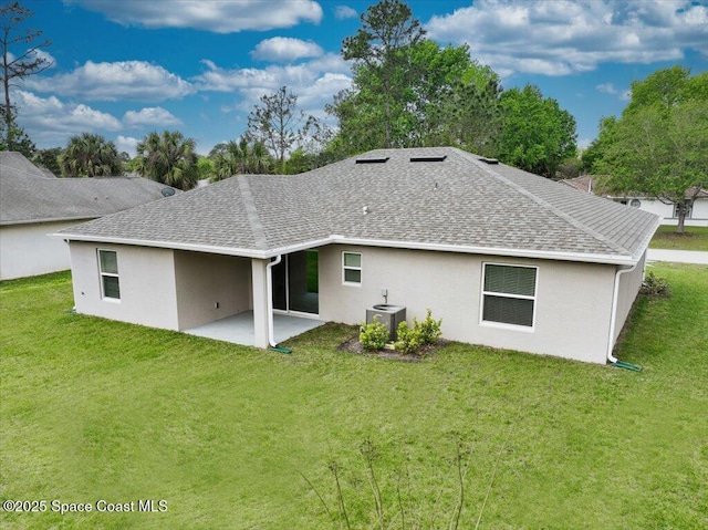 rear view of property featuring a yard, a shingled roof, stucco siding, and a patio