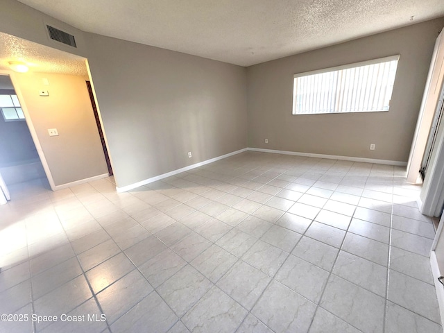 unfurnished room with a textured ceiling, baseboards, visible vents, and a healthy amount of sunlight