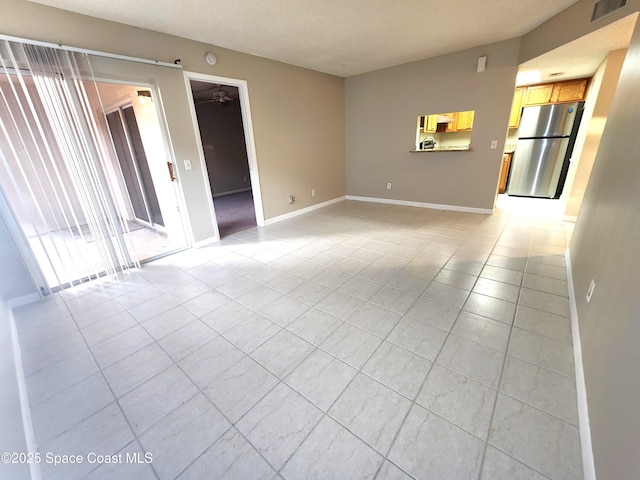 spare room featuring light tile patterned flooring, ceiling fan, visible vents, and baseboards