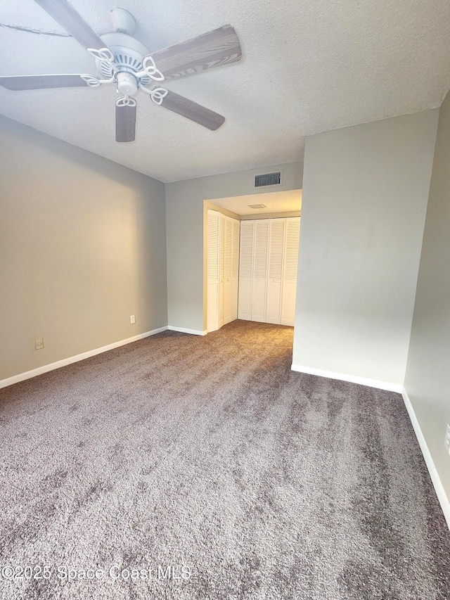 carpeted spare room featuring visible vents, ceiling fan, a textured ceiling, and baseboards