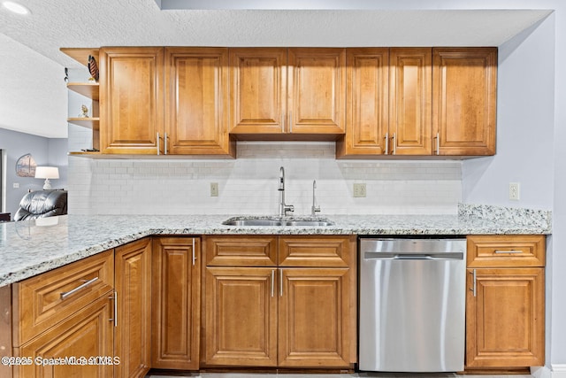 kitchen with brown cabinets, a sink, stainless steel dishwasher, and light stone countertops