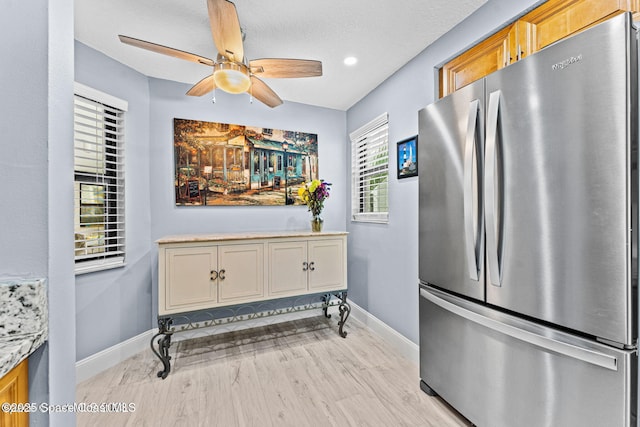 kitchen with ceiling fan, light wood-style flooring, baseboards, light countertops, and freestanding refrigerator