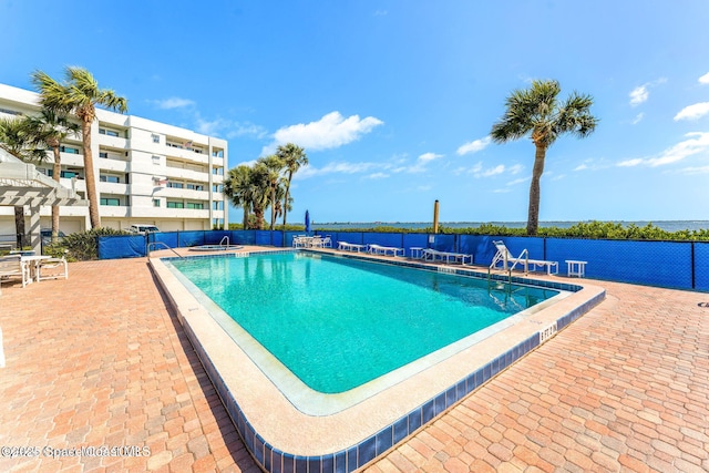 pool featuring a water view, fence, and a patio