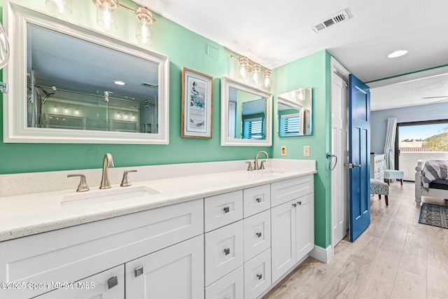 ensuite bathroom with wood finished floors, visible vents, a sink, and double vanity