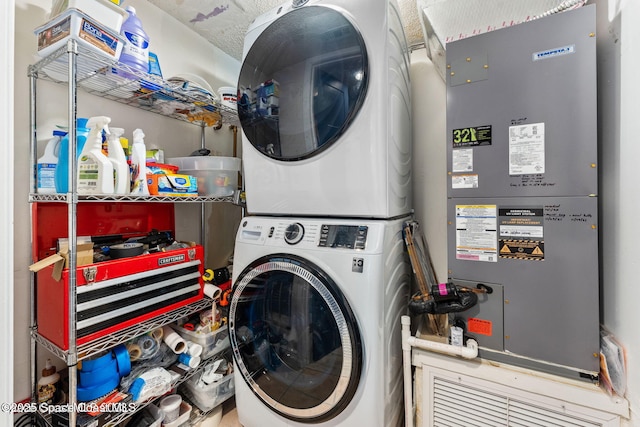 clothes washing area with laundry area, stacked washer and clothes dryer, and heating unit