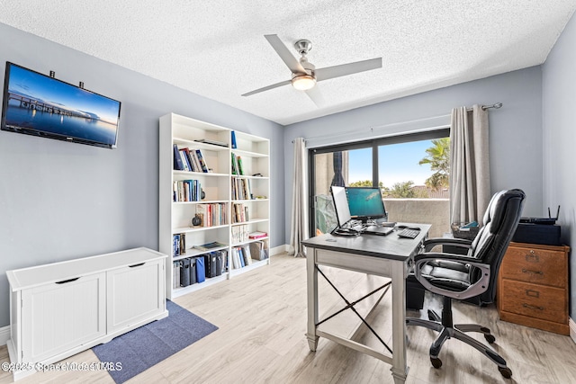 office space with baseboards, ceiling fan, light wood-style flooring, and a textured ceiling