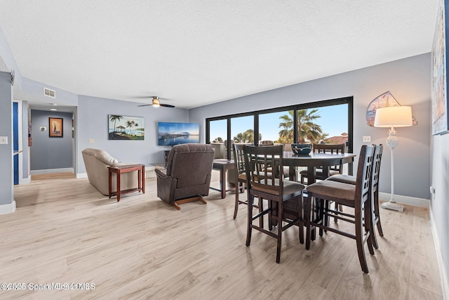 dining area with visible vents, light wood-style flooring, and a textured ceiling