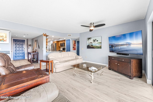 living area with light wood-style flooring, visible vents, baseboards, and ceiling fan