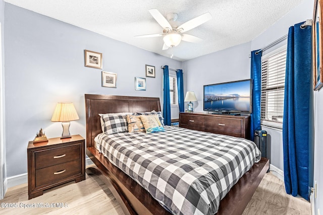 bedroom with a textured ceiling, light wood finished floors, a ceiling fan, and baseboards