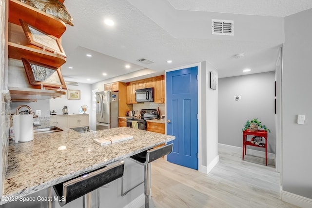 5055 Dixie Hwy NE Unit B206, Palm Bay, FL 32905 - kitchen featuring black appliances, open shelves, baseboards, light wood-type flooring, and a peninsula