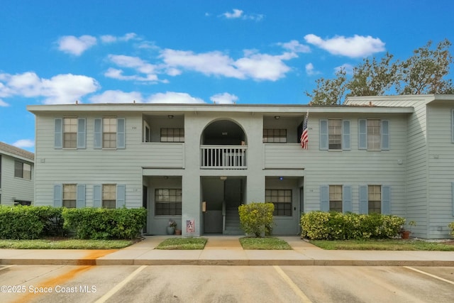 townhome / multi-family property featuring a balcony and uncovered parking