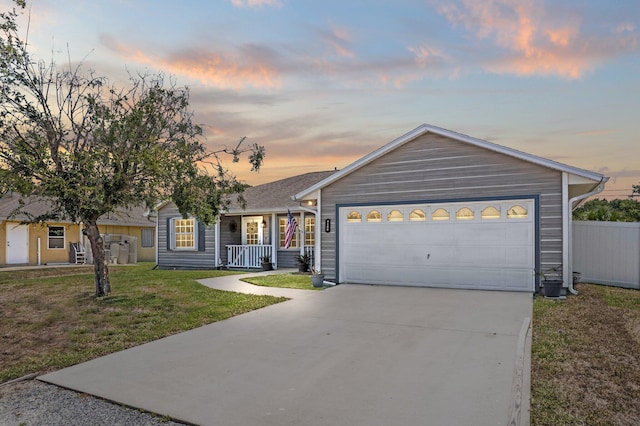 single story home with an attached garage, a porch, concrete driveway, and a yard