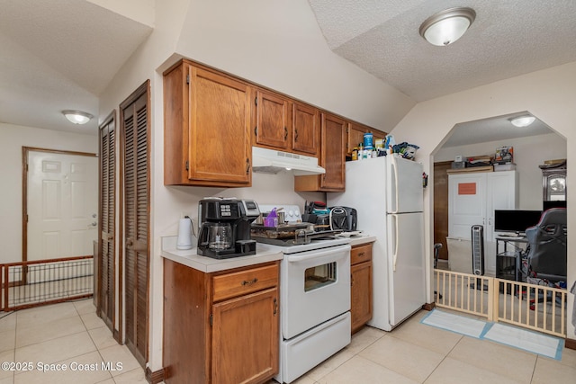 kitchen featuring white appliances, light tile patterned floors, light countertops, a textured ceiling, and under cabinet range hood