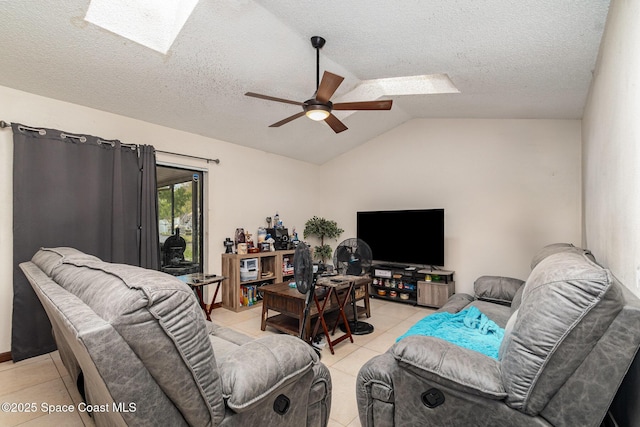 living room featuring lofted ceiling with skylight, ceiling fan, a textured ceiling, and light tile patterned floors