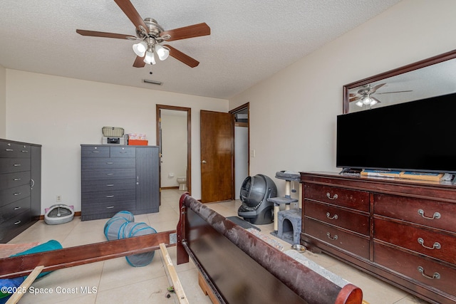 bedroom with ceiling fan, visible vents, a textured ceiling, and light tile patterned flooring