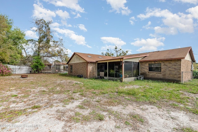 back of property with brick siding, fence, and a sunroom