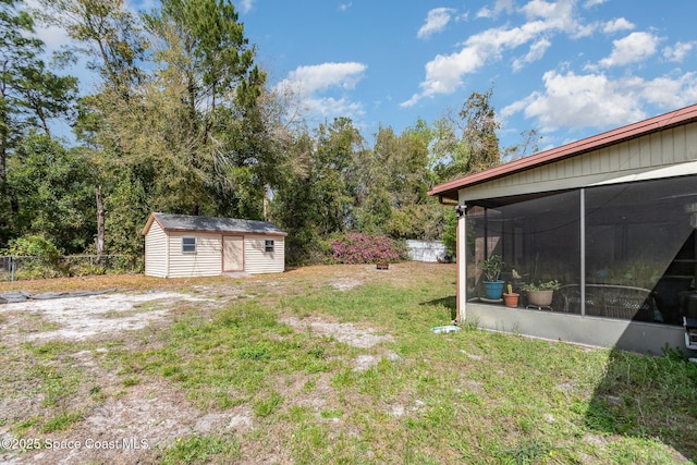 view of yard with a storage shed, fence, a sunroom, and an outdoor structure