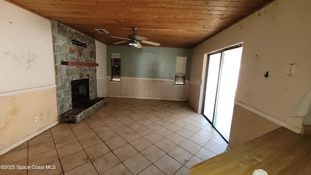 unfurnished living room with a wainscoted wall, a fireplace, light tile patterned floors, visible vents, and wooden ceiling