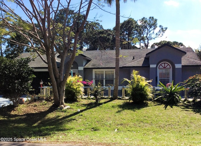 single story home with a shingled roof, a front yard, and stucco siding