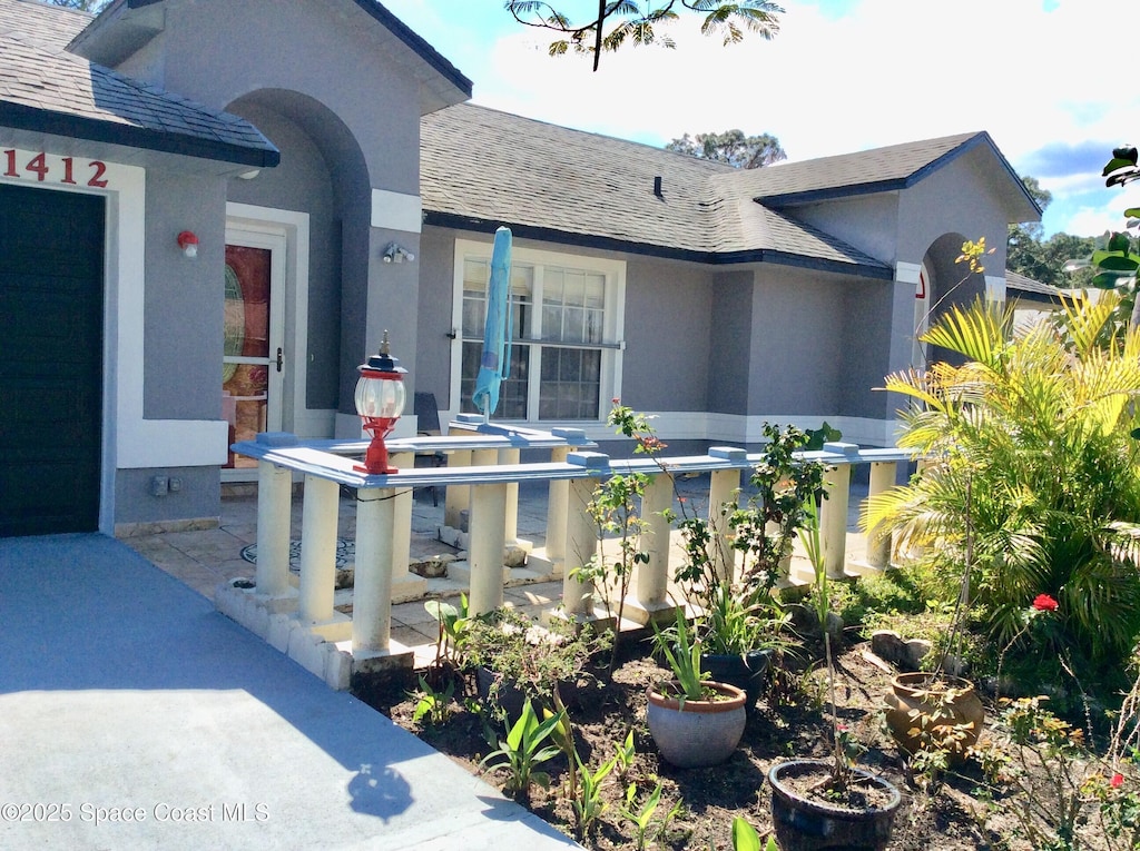 exterior space with a shingled roof and stucco siding