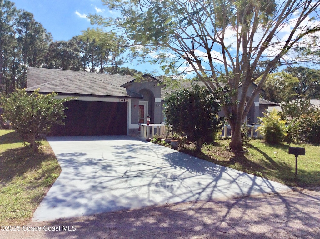 view of front facade with driveway, roof with shingles, and stucco siding