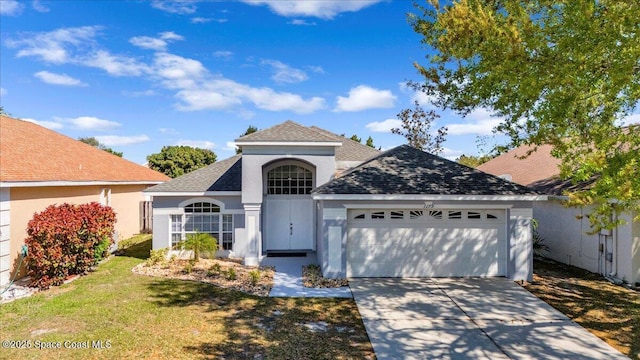 view of front of home with a front yard, roof with shingles, stucco siding, concrete driveway, and a garage