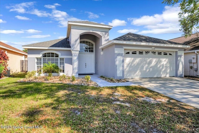 view of front of house with a shingled roof, a front yard, stucco siding, driveway, and an attached garage