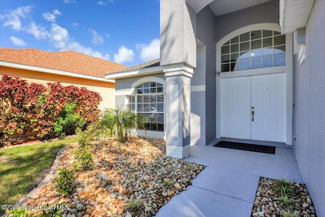 doorway to property featuring a shingled roof and stucco siding