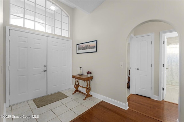 entryway featuring arched walkways, light wood-style flooring, and baseboards