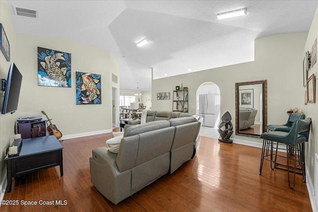 living area featuring visible vents, baseboards, a textured ceiling, and hardwood / wood-style floors