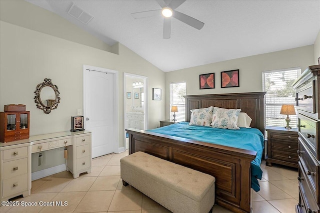 bedroom featuring light tile patterned floors, visible vents, ensuite bathroom, and vaulted ceiling