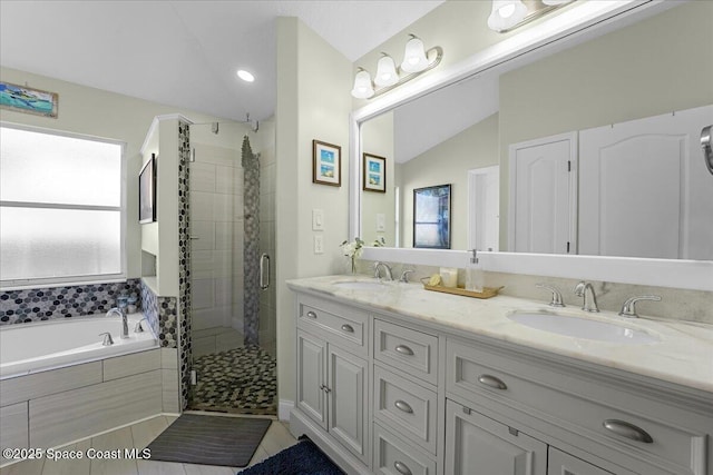 bathroom with double vanity, lofted ceiling, a sink, a shower stall, and a garden tub