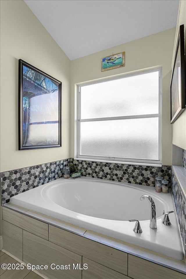 bathroom featuring lofted ceiling and a bath