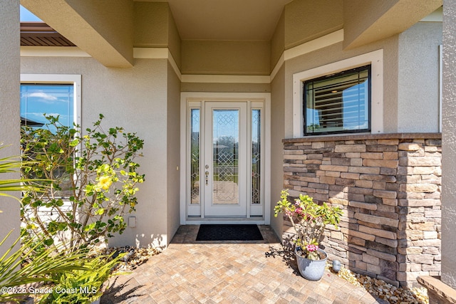 entrance to property featuring stone siding and stucco siding