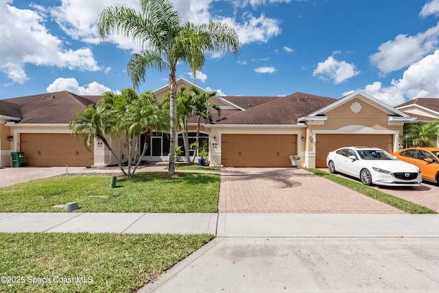 view of front facade featuring an attached garage, decorative driveway, and stucco siding