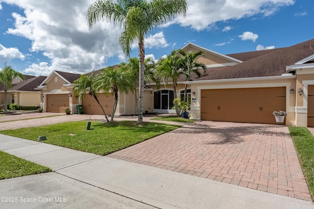 ranch-style house featuring stucco siding, a shingled roof, an attached garage, driveway, and a front lawn